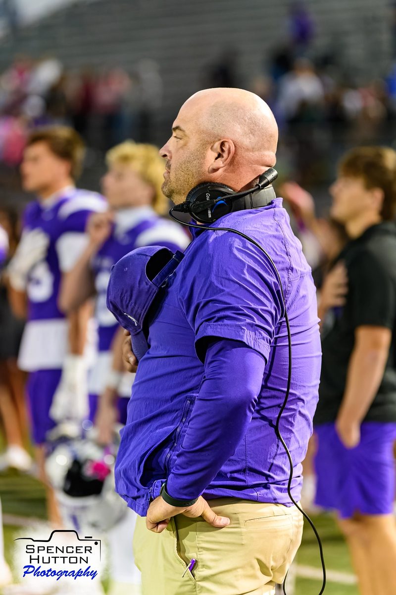 Head coach James Clancy stands for the national anthem before kickoff